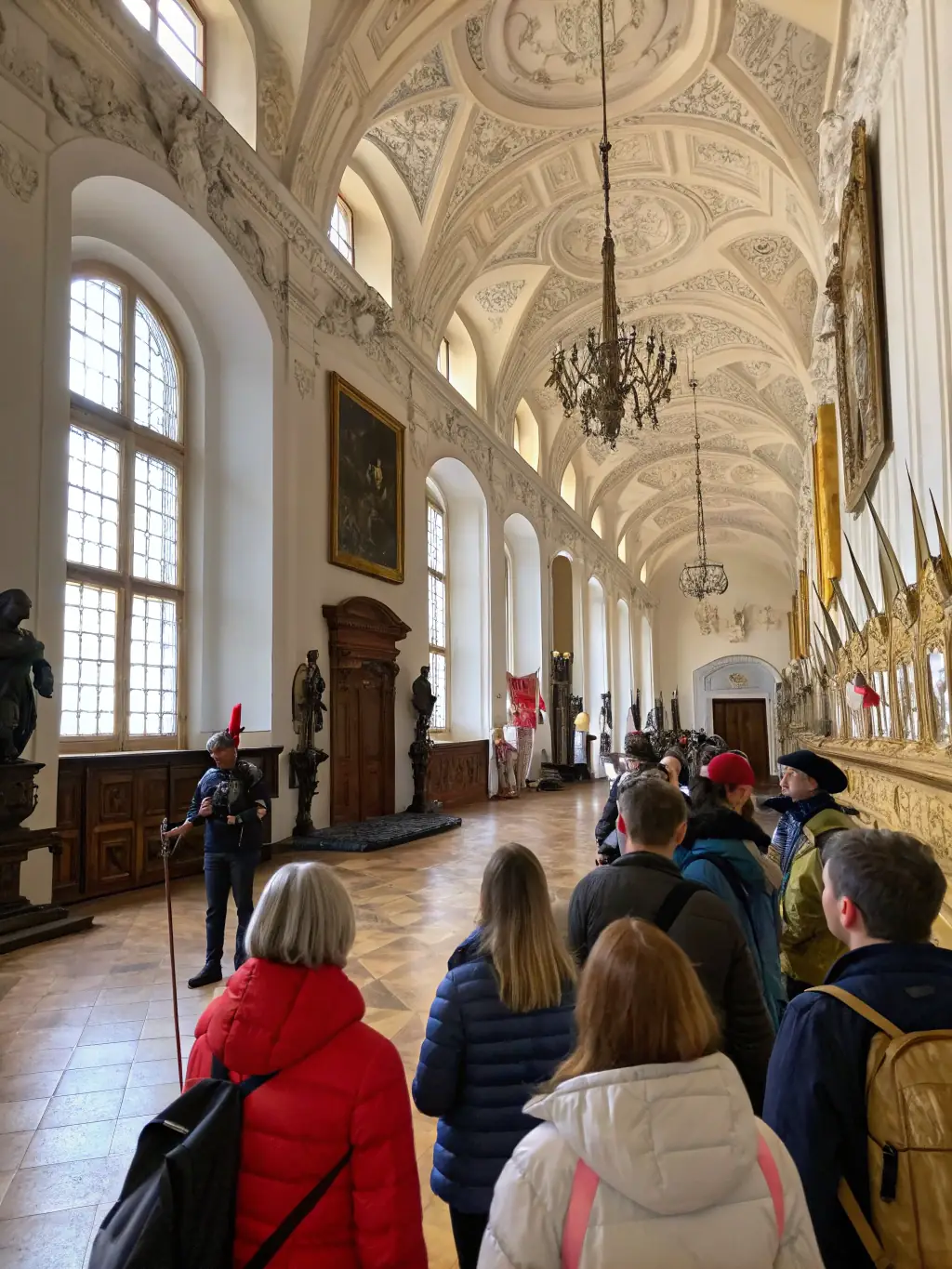 A photograph capturing a group of visitors on a guided tour inside the Château de Dampierre, focusing on the intricate details of the architecture and historical artifacts.
